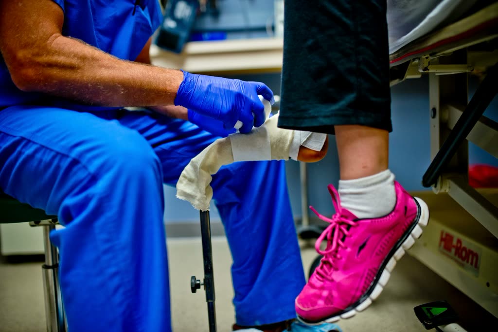 Clinician fitting a supportive dressing on a patient's lower leg